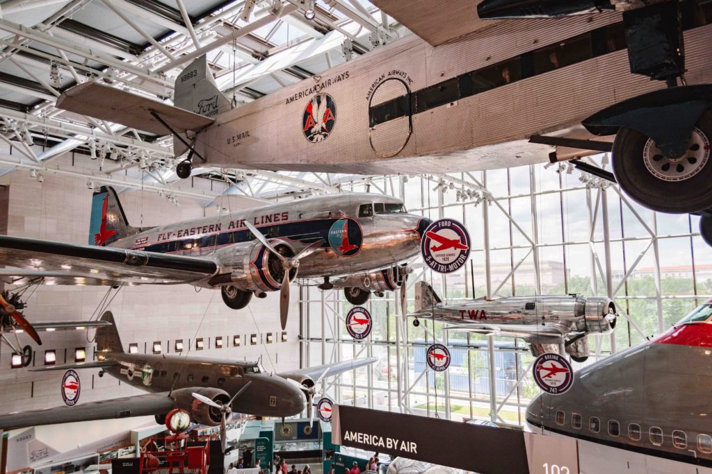 Smithsonian Air and Space Museum airplanes on display hanging in the air with a large glass window behind